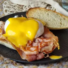 Deliciosos huevos benedictinos con jamón, huevo escalfado y salsa holandesa sobre pan tostado. Un clásico desayuno.