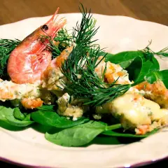 En krämig räkröra med dill, serverad på färsk spenat. Perfekt som sallad till pajen.