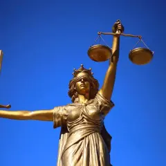 Goldene Justitia-Statue mit Waage und Schwert vor blauem Himmel. Sie verkörpert den **Gericht Gottes**.