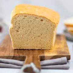 Frisch gebackenes Toastbrot, perfekt für Ihr nächstes Toastbrot Rezept. Auf einem Holzbrett mit Messer und Marmelade im Hintergrund.
