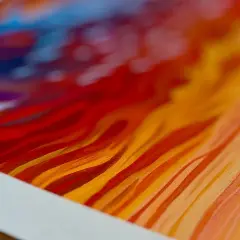 Close-up of a vibrant giclee print, showcasing fiery reds, oranges, and blues in abstract, flowing strokes.