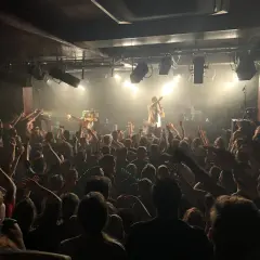 Foule en délire dans une salle de concert, le nombre de places semble limité mais l'ambiance est électrique.