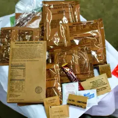 MRE polskie: paczka z daniem "Chicken Pesto Pasta", ciastka, napój, cukier, sól, pieprz i inne dodatki.