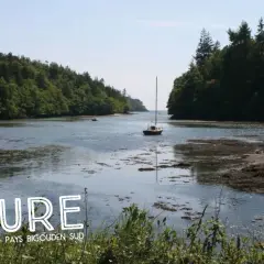 Balade nature dans le **bois de Roscouré**, un voilier navigue sur une rivière bordée de forêts luxuriantes.