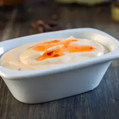 Krämig sås med en virvel av söt chili sås, serverad i en vit skål på en träyta.