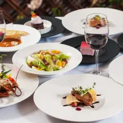 Elegancka kolacja w stylu kuchnia francuska: homar, stek, sałatka Cezar, desery i czerwone wino.