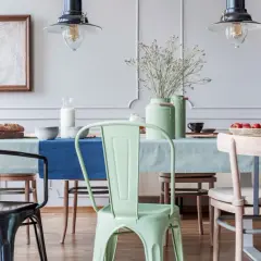 En matsal med olika stolar, en mintgrön stol som ser ut att vara spraymålad, vid ett dukat bord.