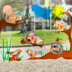 Bunte Fensterbilder basteln Kinder: Eichhörnchen, Igel, Eule & Vögel auf Ästen. Sonnenschein & Wolke im Hintergrund.