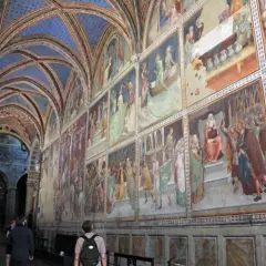 Interno del duomo di San Gimignano con affreschi medievali e volte blu stellate.