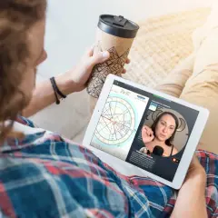Mężczyzna ogląda na tablecie horoskop, gdzie widoczna jest Wenus w Byku. Kobieta tłumaczy astrologiczne niuanse.