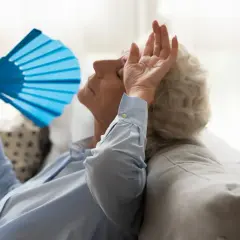Une femme âgée s'évente avec un éventail bleu, montrant les effets de la chaleur sur les personnes âgées.