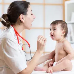 Medico esamina la gola di un bambino con abbassalingua, controllando sintomi di laringite bambini.