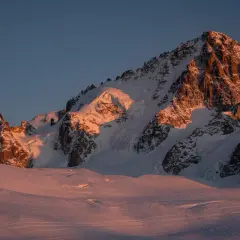 Ośnieżone szczyty Alp oświetlone złotym blaskiem zachodzącego słońca. Widok na trasę Haute Route, gdzie lodowce i skaliste zbocza tworzą majestatyczny krajobraz.