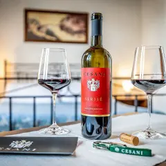 Un calice di vino rosso Cesani, una bottiglia di Serisé Ciliegiolo e un cavatappi, pronti per una degustazione alla Cesani winery.
