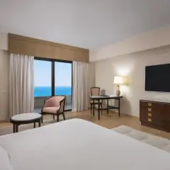 Elegancki pokój z widokiem na morze, idealny na pobyt w Rodos Palace. Wygodne łóżko, stylowe meble i balkon z zapierającym dech w piersiach widokiem.