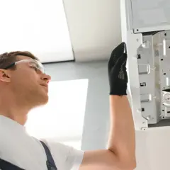 Technik w okularach ochronnych sprawdza bojler, by wyeliminować problem śmierdzącej wody.