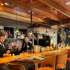Banqueros sirviendo en uno de los restaurantes el ejido, con un ambiente acogedor y una barra de madera pulida.