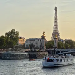 Une belle balade sur Seine à Paris, avec la Tour Eiffel et le pont Alexandre III en arrière-plan. Un bateau navigue paisiblement sur l'eau.