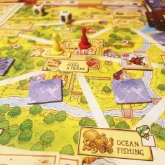Planszowa gra Stardew Valley z pionkami, kostkami i kartami postaci. Na planszy widać rzekę, domy i pola.