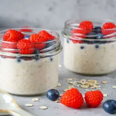 Zwei Gläser mit Overnight Oats, garniert mit Himbeeren und Blaubeeren. Perfekt für gesunde Overnight Oats Rezepte.