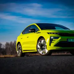 Jaskrawozielony Skoda Enyaq Coupe na tle błękitnego nieba z chmurami i linią energetyczną.