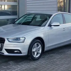 Srebrny Audi A4 B8, model znany z typowych usterek, stoi przed budynkiem.