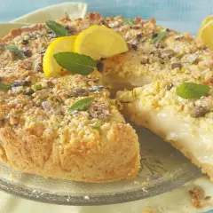 Deliziosa sbriciolata al limone con crema soffice, guarnita con pistacchi, menta e spicchi di limone fresco.