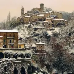 Borgo innevato in Toscana. Case antiche e alberi coperti di neve creano un paesaggio fiabesco, dimostrando che sì, a volte fa neve in Toscana.