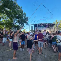 Seifenblasen schweben über einer fröhlichen Menge beim weinturm open air. Kinder und Erwachsene genießen die sommerliche Atmosphäre vor der Bühne.
