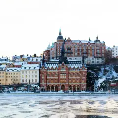 Vinter i Stockholm: snöklädda hus längs vattnet, perfekt för mysiga promenader och fika.