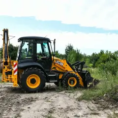 Żółta koparko-ładowarka JCB na placu budowy. Uprawnienia na koparko ładowarkę do czego uprawniają? Do obsługi maszyn budowlanych, takich jak ta.