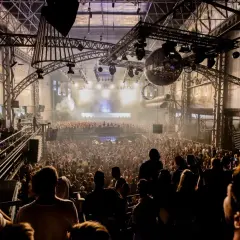 Un'enorme folla balla in una discoteca con luci stroboscopiche e una palla da discoteca scintillante, un'esperienza di **privilege discoteca Ibiza**.