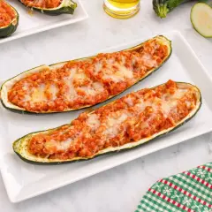 Dos calabacines rellenos de carne y queso gratinado, servidos en un plato blanco.