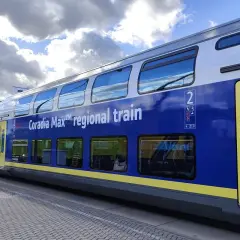 Niebiesko-żółty dwupoziomowy wagon kolejowy Coradia Max™ regional train stoi na peronie.
