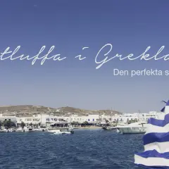 Båtluffa i Grekland: en idyllisk hamn med vita hus, båtar och en grekisk flagga i förgrunden. Den perfekta semestern väntar!