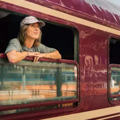 Kvinna med keps lutar sig ut genom fönstret på ett nattåg mot Hamburg, drömmande om äventyr.