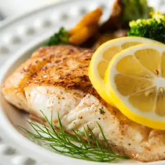 Pieczony halibut z cytryną i koperkiem, podany z pieczonymi ziemniakami i brokułami. Zdrowy posiłek, który nie przekracza halibut kcal.