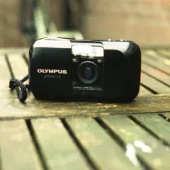 Olympus mju-1 camera, a classic choice for the best film for Olympus Stylus, rests on a weathered wooden surface.