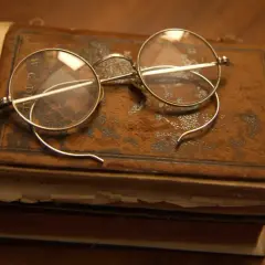 Stare okulary na zabytkowej księdze, jakbyśmy cofali się do czasów, kiedy wynaleziono okulary, by czytać starodruki.