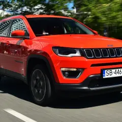 Pomarańczowy Jeep Compass w ruchu. Czy warto kupić ten SUV? Stylowy wygląd i komfort jazdy.