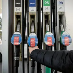 Ręka sięga po dystrybutor paliwa. Wykres cen paliw w Polsce 10 lat pokazuje zmienność kosztów.