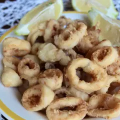 Un piatto invitante di frittura di calamari dorati e croccanti, accompagnati da spicchi di limone fresco.
