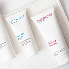 Drei weiße Tuben mit Naturkosmetik, darunter Produkte mit reiner Aloe Vera, liegen auf einem weißen Handtuch.
