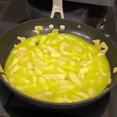 El bacalao al pil pil burbujea en la sartén, con trozos de ajo dorándose en el aceite.