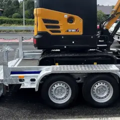 Żółta mini koparka SY18C na przyczepie z rampą. Waga maszyny pozwala na łatwy transport.