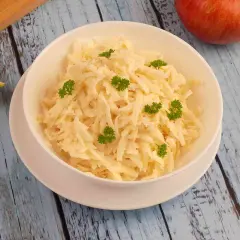 Pyszna surówka z selera i jabłka, udekorowana natką pietruszki, na drewnianym blacie.