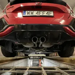 Czerwone auto na podnośniku, podwójny wydech. Zastanawiasz się, ile kosztuje przegląd auta 2026?