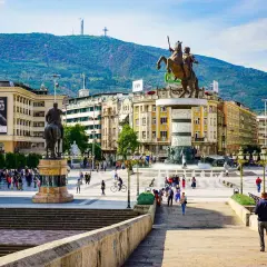 Pomnik wojownika na koniu na placu w Skopje, Macedonia Północna, z górami w tle.