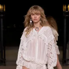 Modelo luce un vestido blanco con encaje, estilo boho, con pendientes largos y collar plateado.