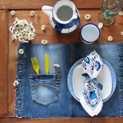 Tovagliette americane fai da te in denim con tasca porta posate, decorate con margherite e un servizio da tavola blu e bianco.
